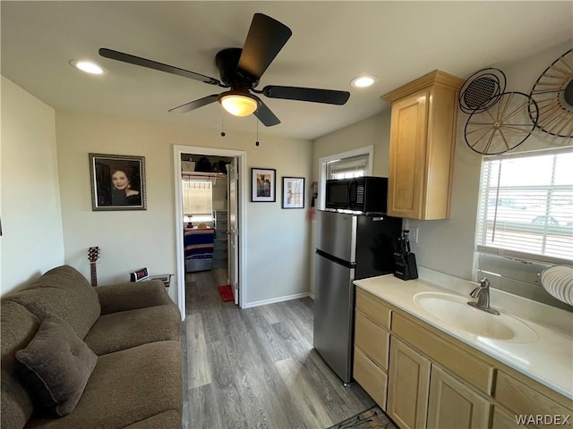 kitchen featuring light countertops, freestanding refrigerator, a sink, wood finished floors, and black microwave