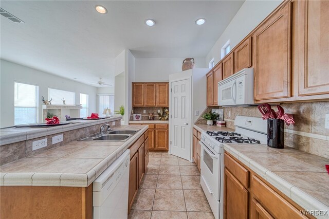 kitchen with tile countertops, white appliances, a sink, and a center island