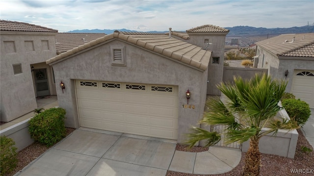 view of front facade featuring driveway, an attached garage, a mountain view, and stucco siding