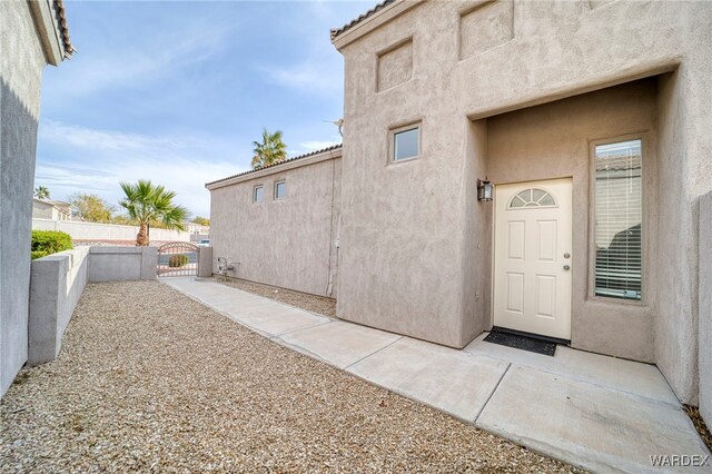 doorway to property with fence, a gate, and stucco siding