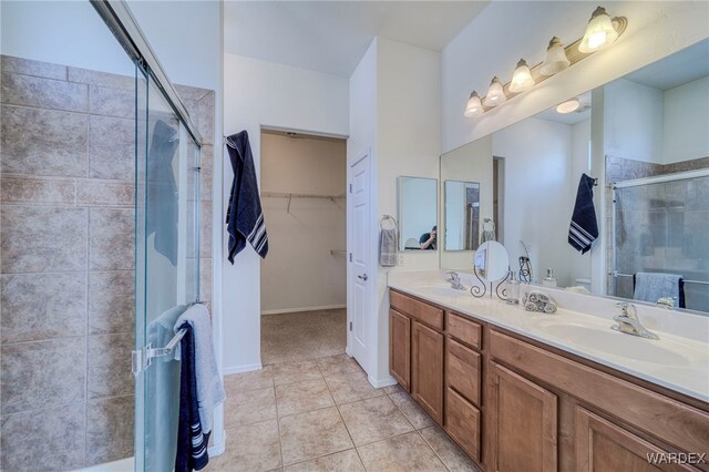 full bathroom with a stall shower, tile patterned flooring, a sink, and a spacious closet