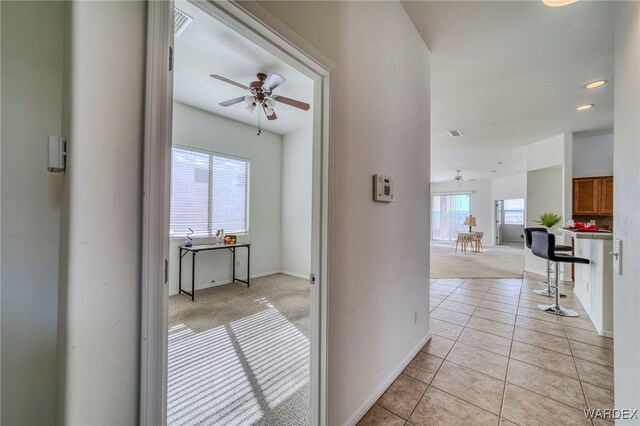 hall with light carpet, baseboards, and light tile patterned flooring