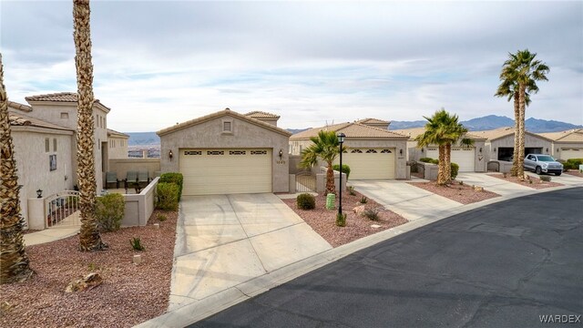 view of front facade with stucco siding, concrete driveway, a mountain view, a garage, and a tiled roof