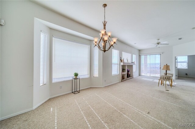 carpeted empty room featuring visible vents, a fireplace, baseboards, and ceiling fan with notable chandelier