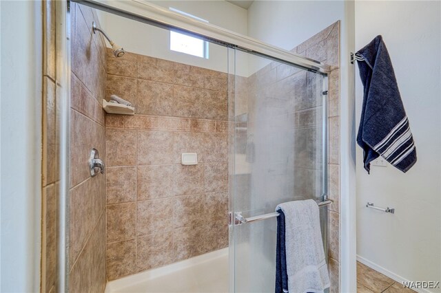 bathroom with a shower with door and tile patterned floors