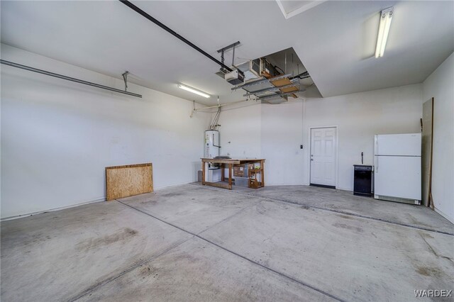 garage featuring a garage door opener, freestanding refrigerator, and water heater