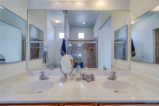 full bathroom with toilet, a sink, visible vents, and a shower stall