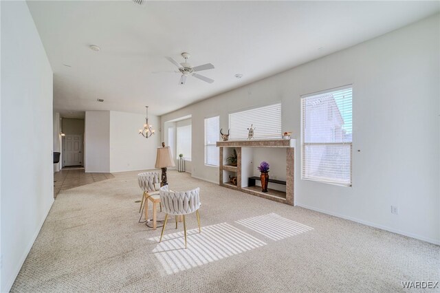 interior space featuring a healthy amount of sunlight, carpet flooring, baseboards, and ceiling fan with notable chandelier