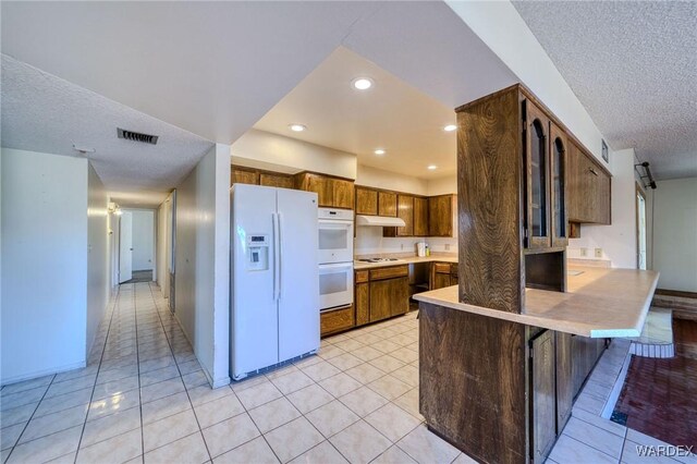 kitchen featuring white appliances, a barn door, visible vents, a peninsula, and light countertops