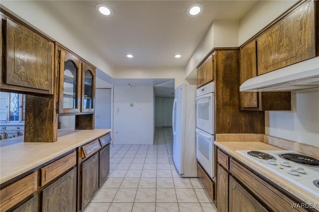 kitchen featuring light tile patterned floors, recessed lighting, white appliances, light countertops, and brown cabinets