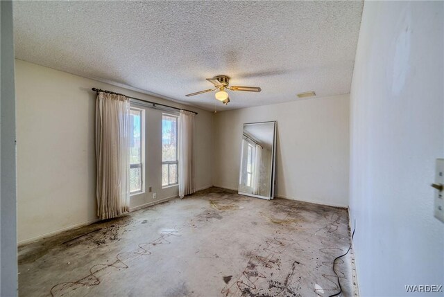 empty room with a ceiling fan, visible vents, concrete floors, and a textured ceiling