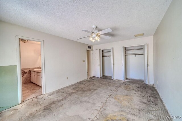 unfurnished bedroom featuring a textured ceiling, concrete floors, two closets, and visible vents