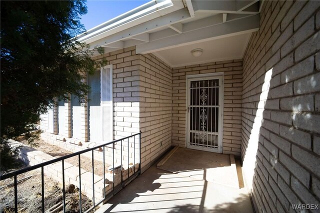 view of exterior entry with brick siding and a balcony