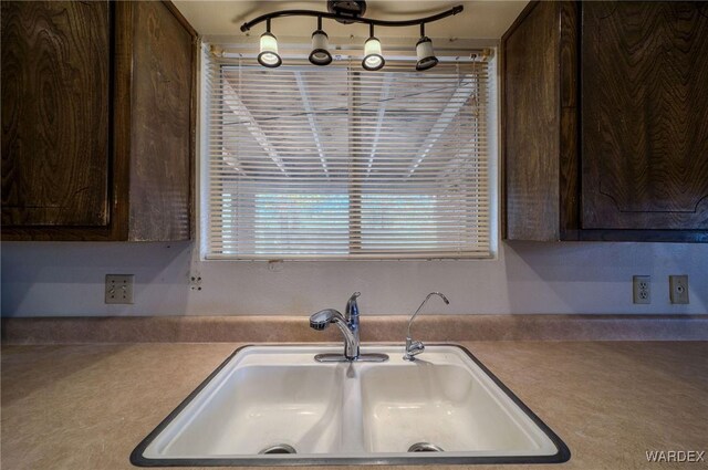 kitchen featuring dark brown cabinets, light countertops, and a sink