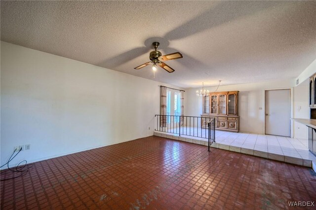 spare room with a textured ceiling and ceiling fan with notable chandelier