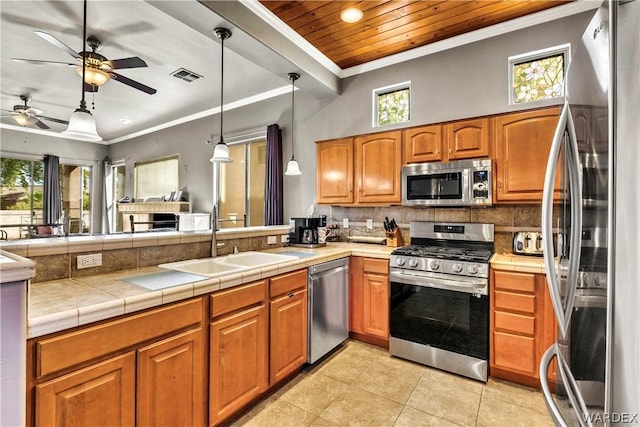 kitchen with appliances with stainless steel finishes, a sink, decorative light fixtures, and brown cabinets