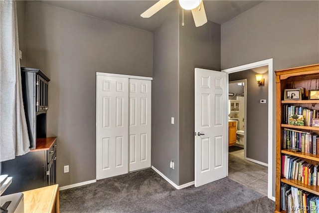 interior space with a towering ceiling, baseboards, dark carpet, and a closet