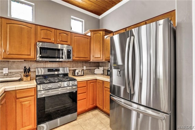 kitchen with ornamental molding, stainless steel appliances, backsplash, and light tile patterned flooring