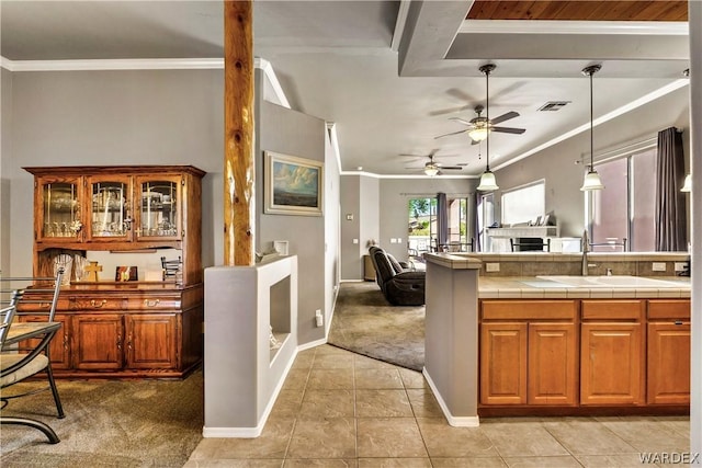 kitchen with light colored carpet, ornamental molding, brown cabinets, open floor plan, and a sink