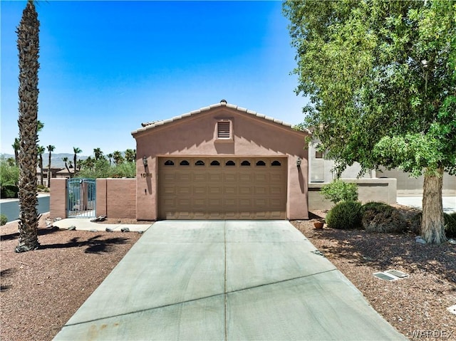 view of front of house featuring a garage, concrete driveway, a gate, and stucco siding