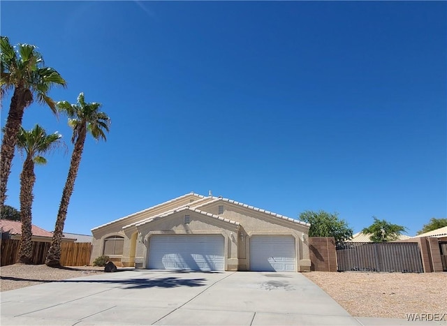 view of front of house with a garage, concrete driveway, fence, and stucco siding