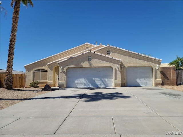 view of front facade with a garage, driveway, fence, and stucco siding