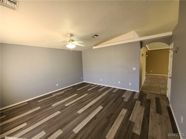 spare room with lofted ceiling, visible vents, arched walkways, and ceiling fan