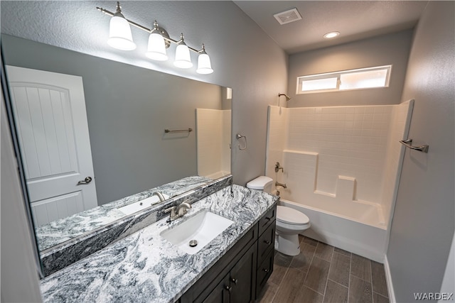 bathroom featuring toilet, wood finish floors, visible vents, vanity, and bathing tub / shower combination