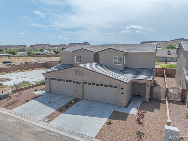 view of front of home with stucco siding, concrete driveway, a mountain view, fence, and a garage