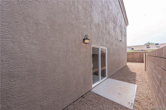 view of side of property featuring a fenced backyard, a patio, and stucco siding