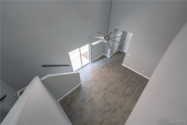 unfurnished living room featuring baseboards, dark wood finished floors, a high ceiling, and ceiling fan