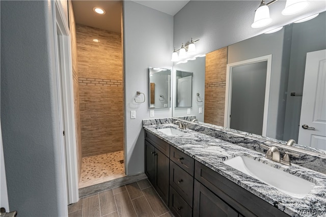 bathroom featuring double vanity, walk in shower, a sink, and wood finish floors