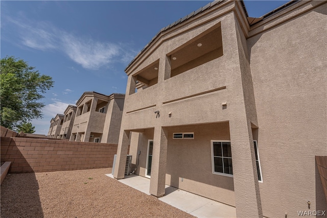 rear view of property featuring central AC unit, fence, a patio, and stucco siding