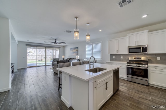 kitchen with visible vents, decorative backsplash, appliances with stainless steel finishes, open floor plan, and a sink