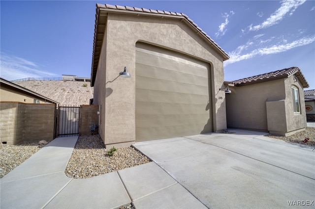 garage with a gate, driveway, and fence