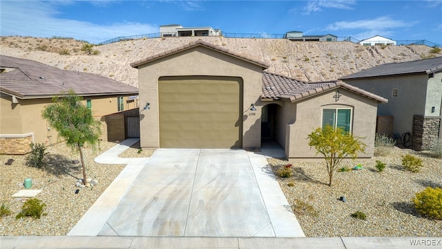 view of front facade with driveway, a tile roof, an attached garage, and stucco siding