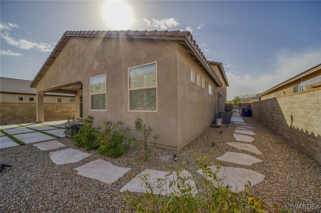 view of home's exterior with a tile roof, stucco siding, central AC, a patio area, and a fenced backyard