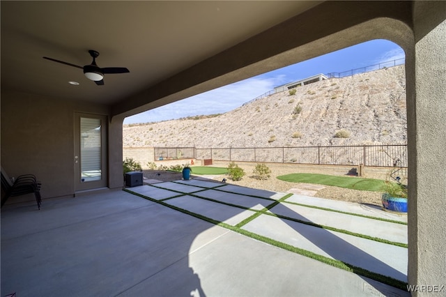 view of patio featuring a ceiling fan, a fenced backyard, and a mountain view