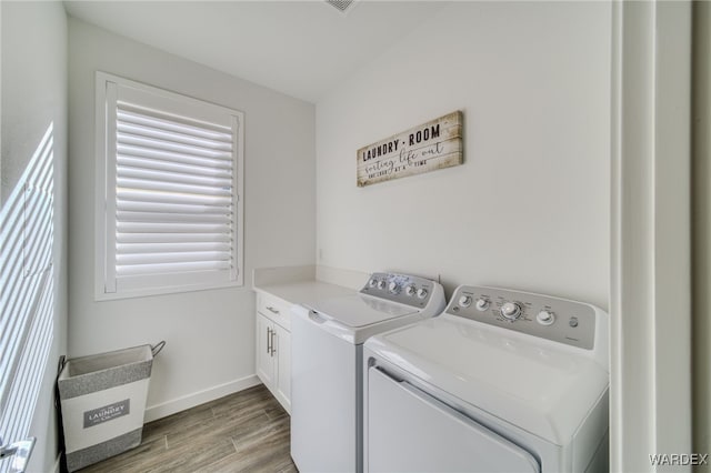 clothes washing area featuring baseboards, wood finished floors, cabinet space, and washer and dryer