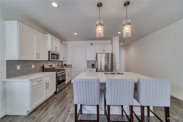 kitchen with stainless steel appliances, light countertops, a sink, and tasteful backsplash