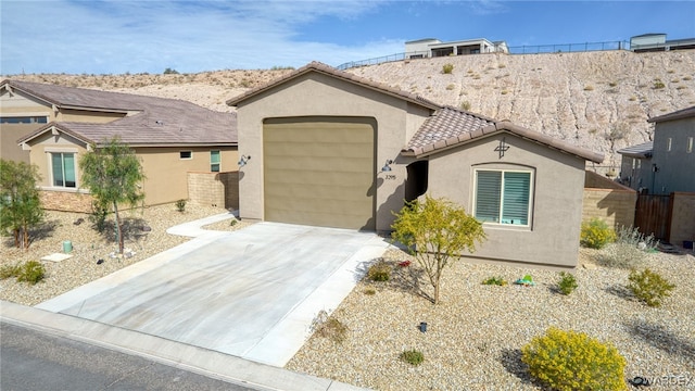 view of front of house with fence, driveway, a tiled roof, and stucco siding