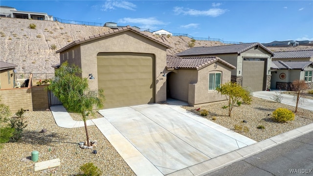 view of front of house with a tile roof, stucco siding, concrete driveway, fence, and a garage