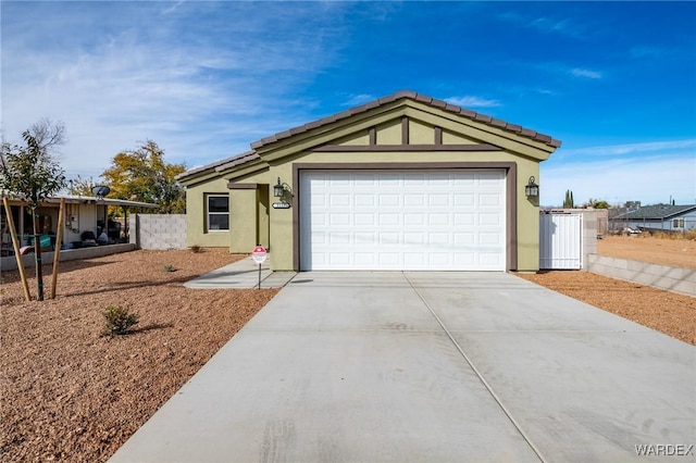 ranch-style house with driveway, an attached garage, and stucco siding