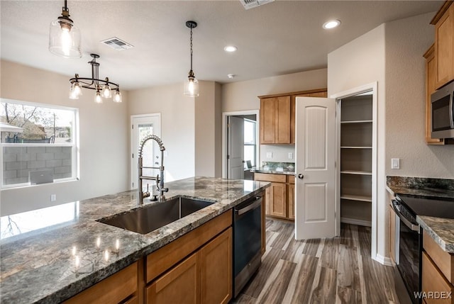 kitchen featuring visible vents, dishwasher, electric range oven, hanging light fixtures, and a sink