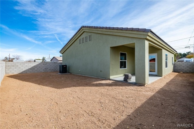 back of house featuring central AC, a patio, a fenced backyard, and stucco siding