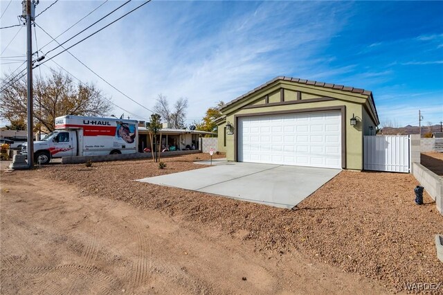 single story home with concrete driveway, an outdoor structure, fence, and stucco siding