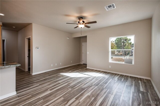 unfurnished room with ceiling fan, wood finished floors, visible vents, and baseboards