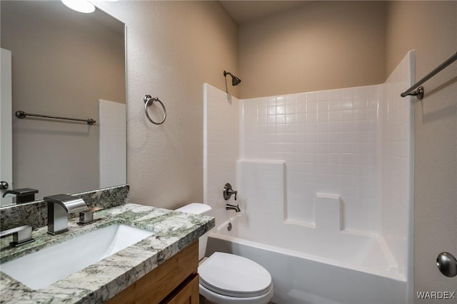 full bath featuring toilet, a textured wall, bathtub / shower combination, and vanity