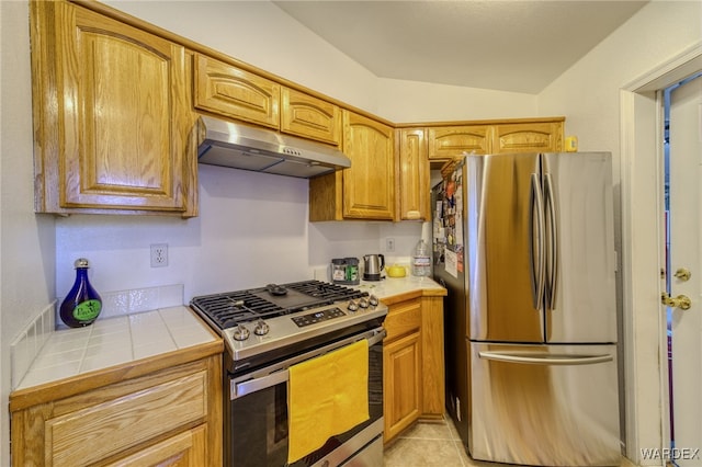 kitchen featuring under cabinet range hood, appliances with stainless steel finishes, tile counters, and light tile patterned flooring