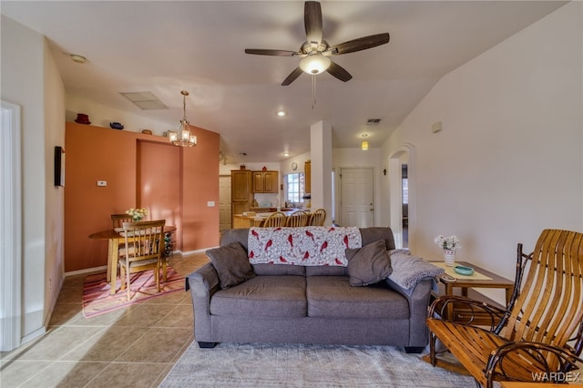 living area with arched walkways, ceiling fan, light tile patterned floors, visible vents, and baseboards